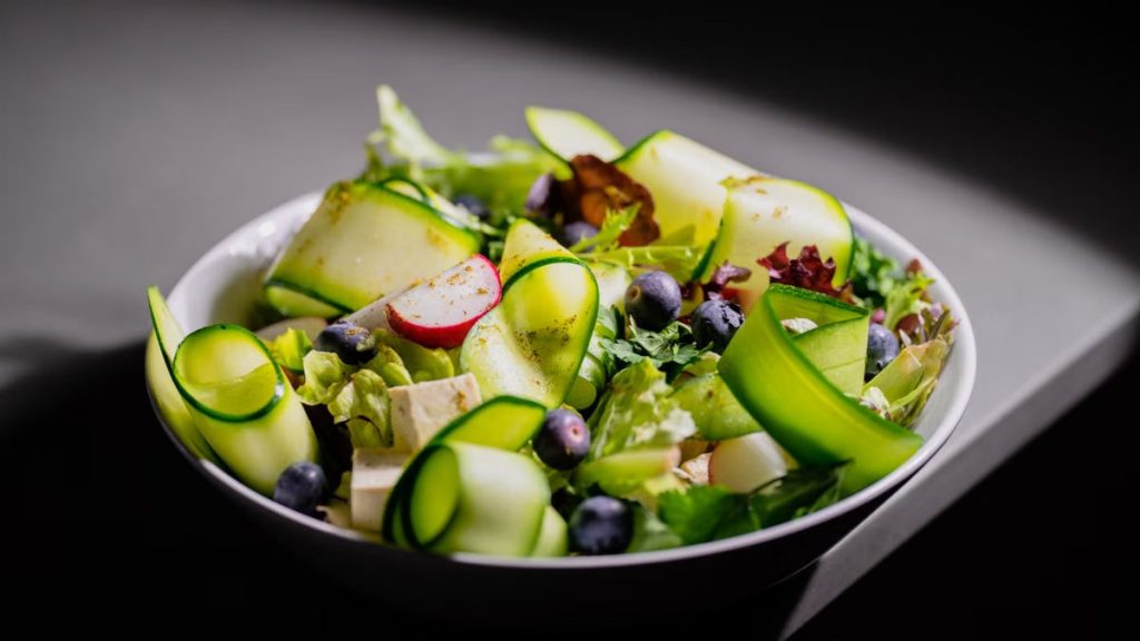 Delicious fresh salad with zucchini ribbons, radish, blueberries, and feta cheese, perfect for a healthy meal.