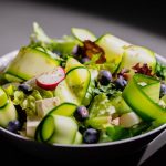 Delicious fresh salad with zucchini ribbons, radish, blueberries, and feta cheese, perfect for a healthy meal.